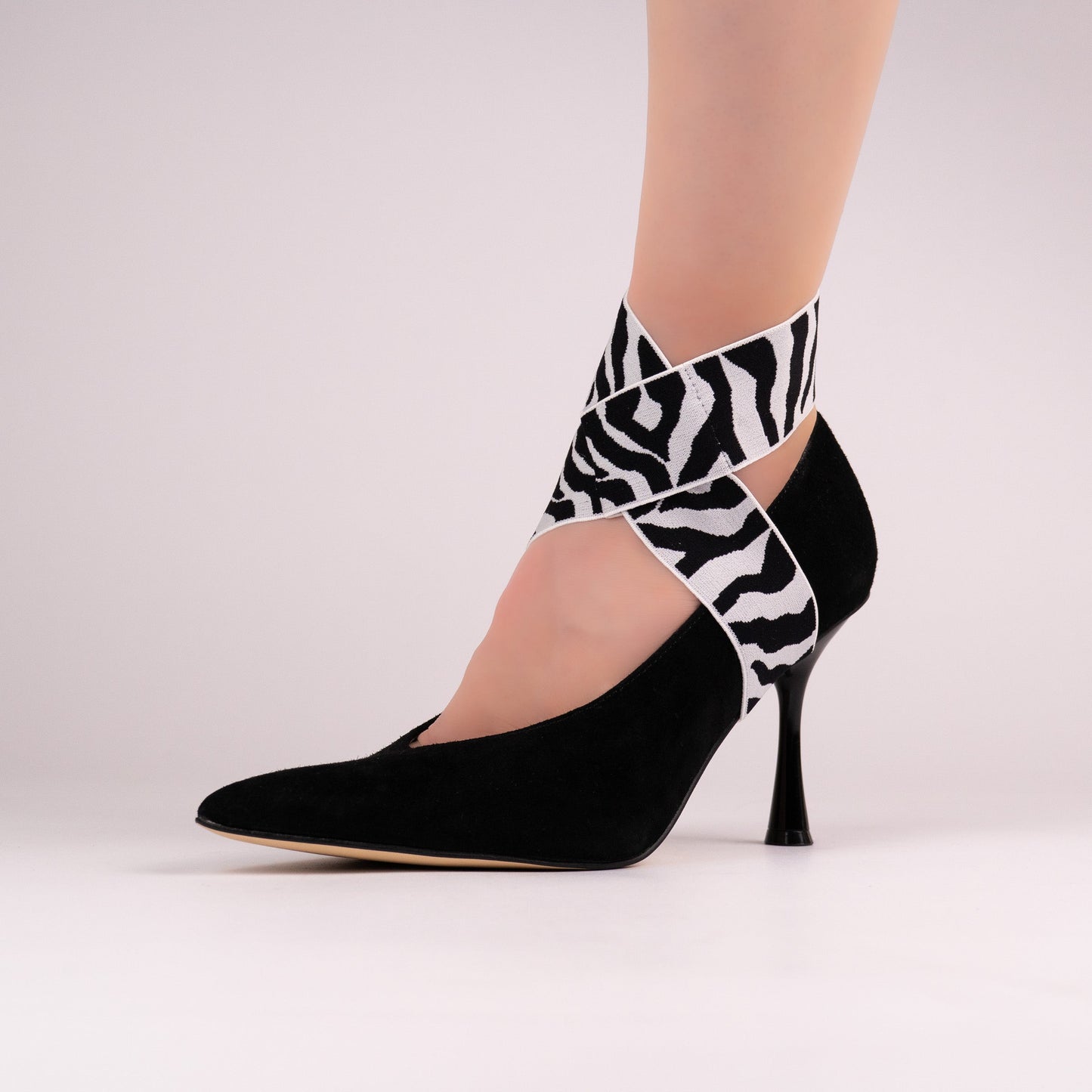Black-and-white zebra LYNKS shoe straps styled on a black pointed-toe pump