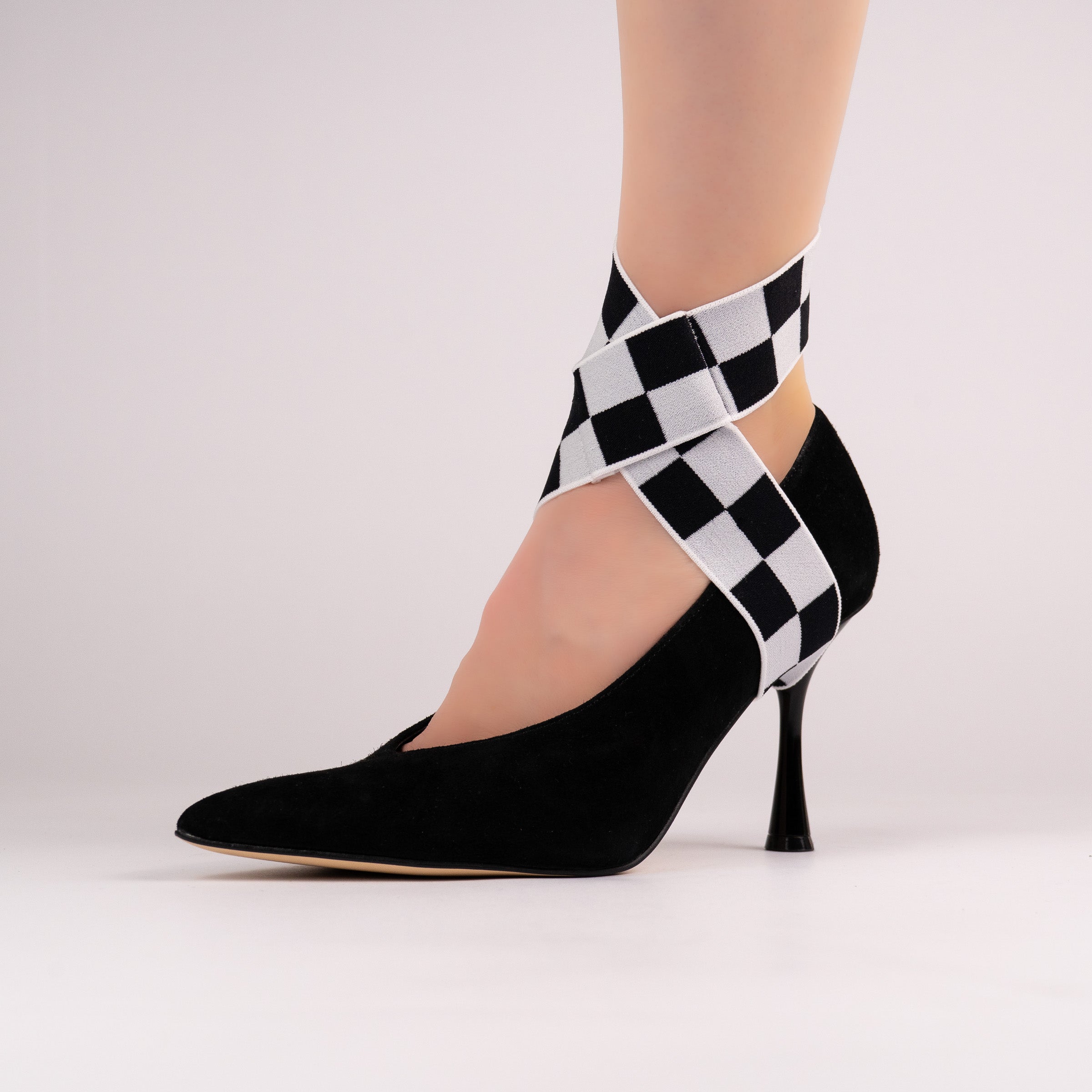 Black-and-white checker LYNKS straps styled on a black pointed-toe pump